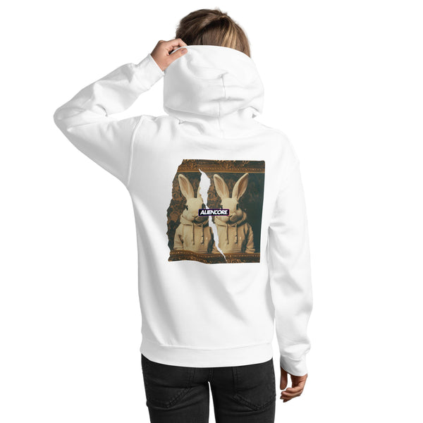 Person wearing a white hoodie with a graphic design on the back against a white brick wall.