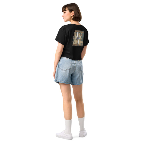 Person wearing a black t-shirt with a graphic design on the back and denim shorts on a white background