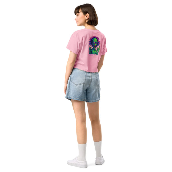 Person wearing a pink t-shirt with a graphic design on the back and denim shorts on a white background