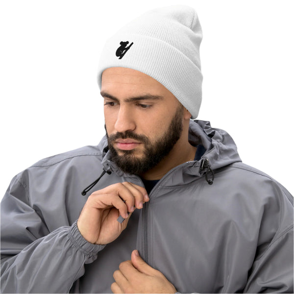 Man wearing a white beanie with a logo and a gray jacket on a light gray background