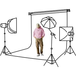 Person in a pink hoodie standing in front of a photography studio setup with lights and reflectors.