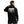 Person wearing a black hoodie with a graphic design on the back against a white brick wall.