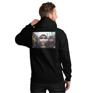 Person wearing a black hoodie with a graphic design on the back against a white brick wall.