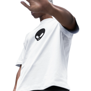 Person wearing a white t-shirt with an alien graphic, standing outdoors.