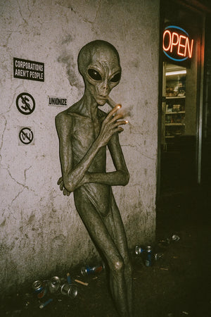 Statue of an alien figure smoking a cigarette in a setting with posters and a 'Open' sign.