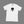White t-shirt with black alien logo on a light gray surface with accessories around